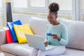 Young woman holding credit card and using laptop computer. Online shopping concept. Beautiful black girl holding credit card and Royalty Free Stock Photo