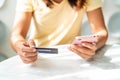 Young woman holding a credit card and using smart phone for make an online shopping payment at home Royalty Free Stock Photo