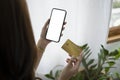 Woman holding credit card and using smart phone for shopping online at home. Royalty Free Stock Photo