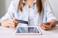 Young woman holding a credit card and using smartphone for making online payment Royalty Free Stock Photo