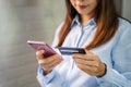 Young woman holding a credit card and using smartphone for making online payment shopping Royalty Free Stock Photo