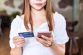 Young woman holding a credit card and using smartphone for making online payment shopping in restaurant Royalty Free Stock Photo