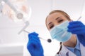 Young woman holding dental mirror while leaning to her patient