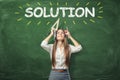 Young woman holding different office supplies in hands and standing under the word'solution' written above her head. Royalty Free Stock Photo