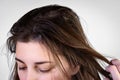 Young woman holding dirty greasy hair on gray background.