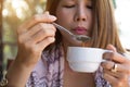 Young woman holding drinking coffee using spoon blowing hot coffee before drinking in the morning at home..Asian girl drinking Royalty Free Stock Photo