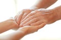 Young woman holding elderly man hands on blurred background, closeup. Help service Royalty Free Stock Photo