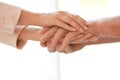 Young woman holding elderly man hands on blurred background, closeup. Help service Royalty Free Stock Photo