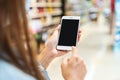 Young woman holding the empty screen smart phone while shopping in grocery store Royalty Free Stock Photo