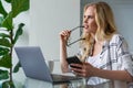 young woman holding eyeglasses and looking away while working with digital devices