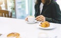 Young woman holding in female hands croissant and drink hot aroma coffee or tea in breakfast time, hipster traveler smile girl Royalty Free Stock Photo