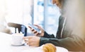 Young woman holding in female hands mobile phone and drink hot aroma coffee or tea in breakfast time, hipster traveler girl Royalty Free Stock Photo