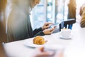 Young woman holding in female hands mobile phone and drink hot aroma coffee or tea in breakfast time, hipster traveler girl Royalty Free Stock Photo