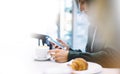 Young woman holding in female hands mobile phone and drink hot aroma coffee or tea in breakfast time, hipster traveler girl Royalty Free Stock Photo