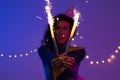 Young woman holding festive Christmas sparklers in hands. New year, Birthday