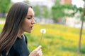 A young woman holding a flowering dandelion in her hand and blowing on a flower Royalty Free Stock Photo