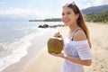 Young woman holding a fresh green coconut enjoying drinking on the beach Royalty Free Stock Photo