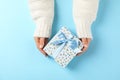 Young woman holding gift box on light blue background Royalty Free Stock Photo