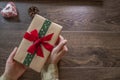 Young woman holding gift box with red and green ribbon on wooden background Royalty Free Stock Photo