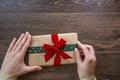 Young woman holding gift box with red and green ribbon on wooden background Royalty Free Stock Photo