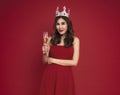 Young woman holding glasses of champagne and smiling while celebrating on red background. christmas and happy new year concept Royalty Free Stock Photo