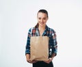 Young woman is holding grocery shopping bag on white background. Young girl is looking in camera Royalty Free Stock Photo