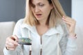 Young woman holding hair and looking at comb in surprise Royalty Free Stock Photo