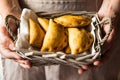 Young woman holding in hands wicker basket with freshly baked empanadas turnover pies with vegetables kinfolk Royalty Free Stock Photo