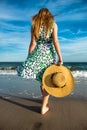 Young woman holding hat and walking on beach sand to the ocean Royalty Free Stock Photo