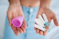 Young woman holding at her hands menstrual cup and tampons