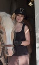 Young woman holding her horse in front of the stable Royalty Free Stock Photo