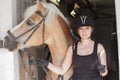 Young woman holding her horse in front of the stable Royalty Free Stock Photo