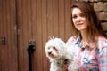 Young woman holding her little dog and standing at brick wall Royalty Free Stock Photo