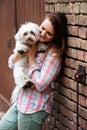 Young woman holding her little dog and standing at brick wall Royalty Free Stock Photo