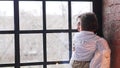 A young woman holding her toddler son, pointing through the window