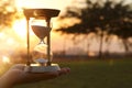 Young woman holding Hourglass during sunset. vintage style. Royalty Free Stock Photo