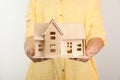 Young woman holding house model on light background Royalty Free Stock Photo