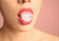 Young woman holding ice cube in mouth on color background Royalty Free Stock Photo