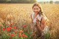 Young woman holding Jack Russell terrier puppy on her hands, sunset lit wheat field in background, some red poppy flowers in front Royalty Free Stock Photo