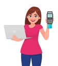 Young woman holding laptop computer and showing credit, debit or ATM card payment machine. POS terminal. Trendy girl using digital Royalty Free Stock Photo