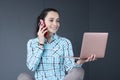Young woman holding laptop in her hands and talking on phone Royalty Free Stock Photo