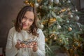 Young woman holding light garland over Christmas tree