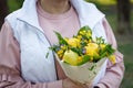 Young woman is holding a lovely bouquet of yellow and blue flowers, pears and lemons