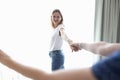 Young woman holding man hand near window at home Royalty Free Stock Photo