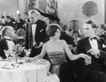 Young woman holding a man's hand at a different table while her companion is talking to the waiter Royalty Free Stock Photo