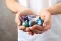 Young woman holding many beautiful gemstones on beige background