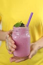 Young woman holding jar of tasty blackberry smoothie, closeup