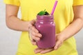 Young woman holding mason jar of tasty blackberry smoothie