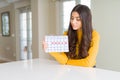 Young woman holding menstruation calendar with a confident expression on smart face thinking serious