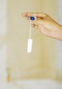 Young woman holding a menstruation cotton tampon in her hand ready to be used
